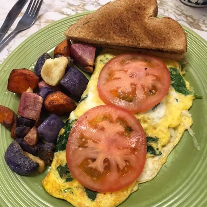 spinach omelette topped with sliced tomato and root veggies