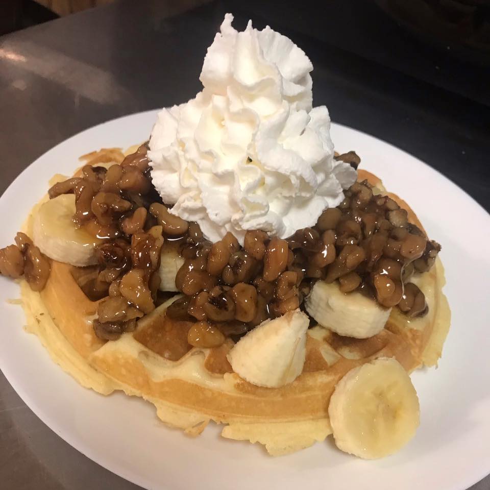 waffle topped with nuts bananas and whip cream